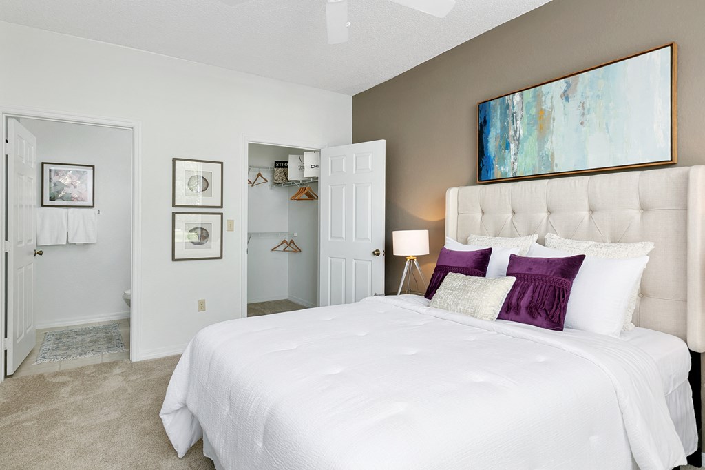 a bedroom with a large white bed and purple pillows