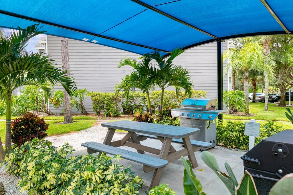 a picnic table with a grill under a blue roof
