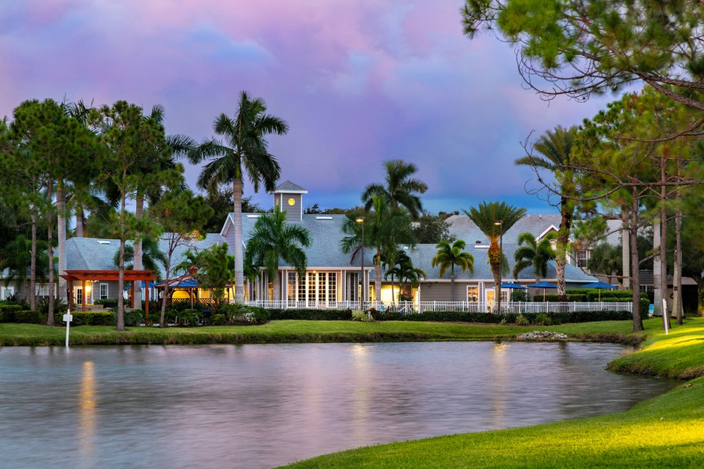 a large house with palm trees and a lake at dusk