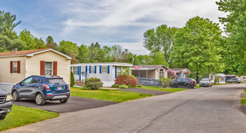 A suburban street with houses and cars parked on the side.