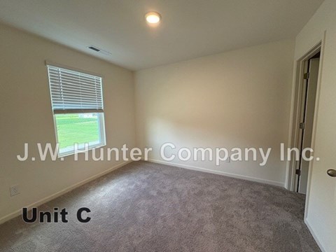 A room with a window showing a green lawn outside and a carpet on the floor.