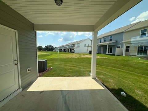 A view from a doorway looking out to a grassy area with houses in the distance.