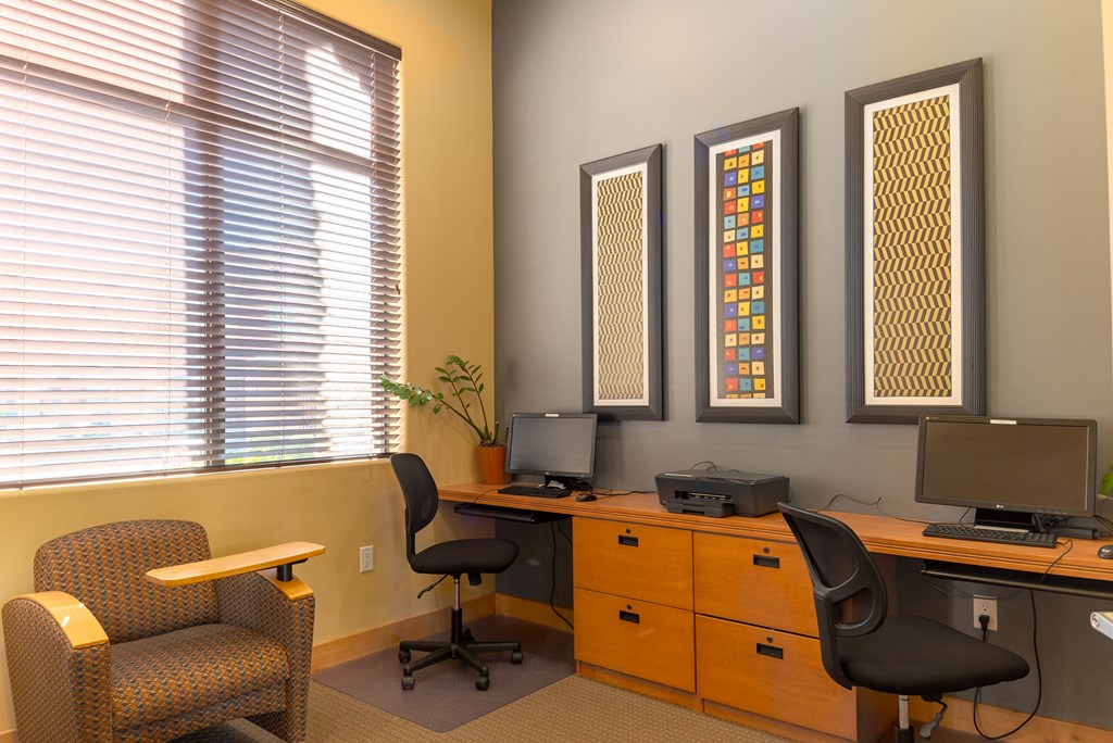 a desk with two computer monitors and two chairs