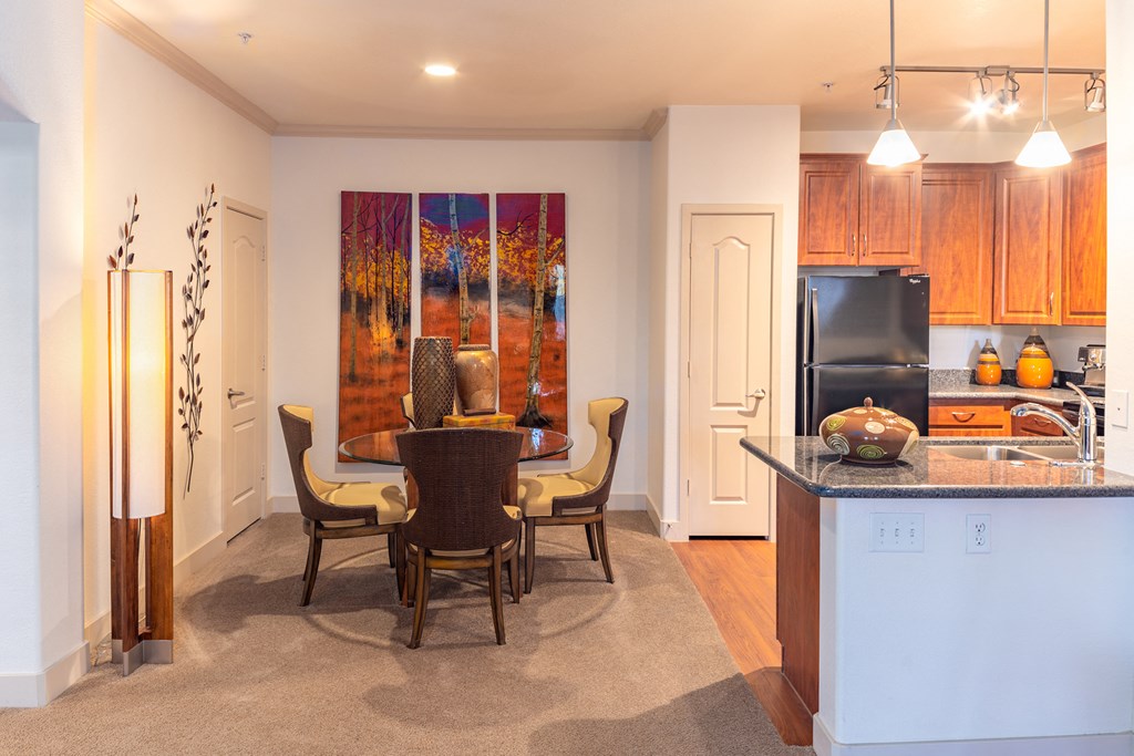 a kitchen and dining room with a table and chairs and a painting on the wall