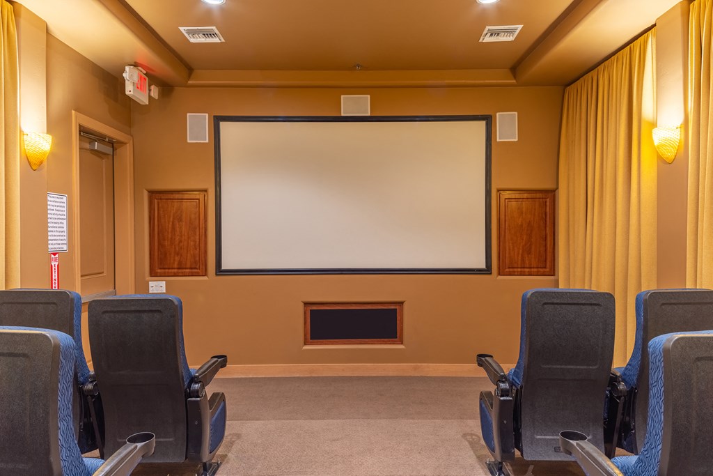 a theater room with chairs and a large screen