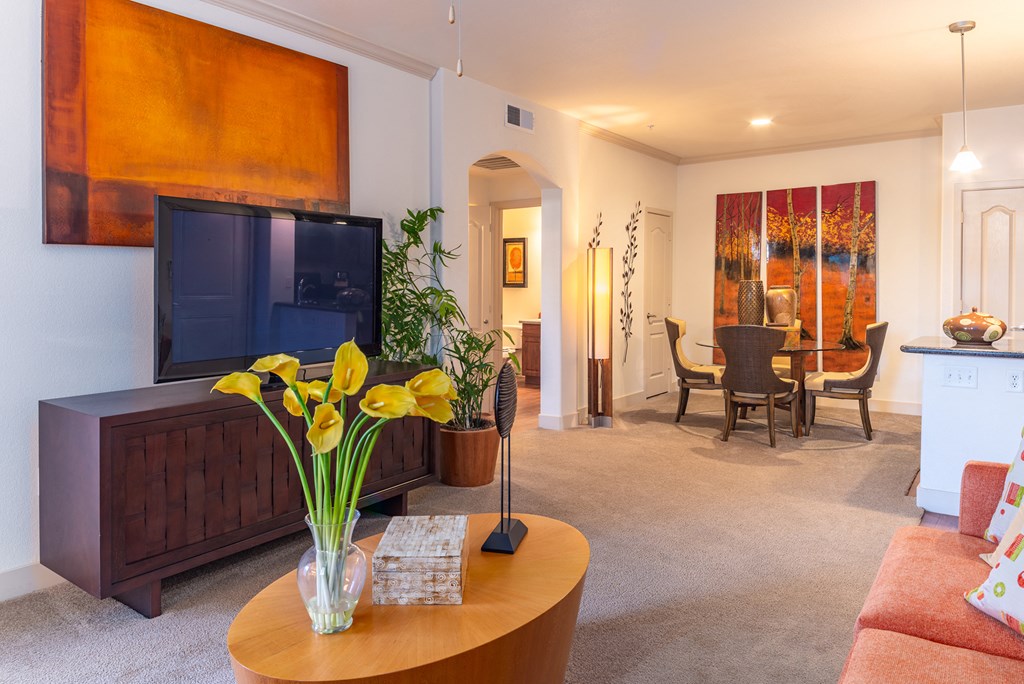 a living room with a tv and a dining room in the background