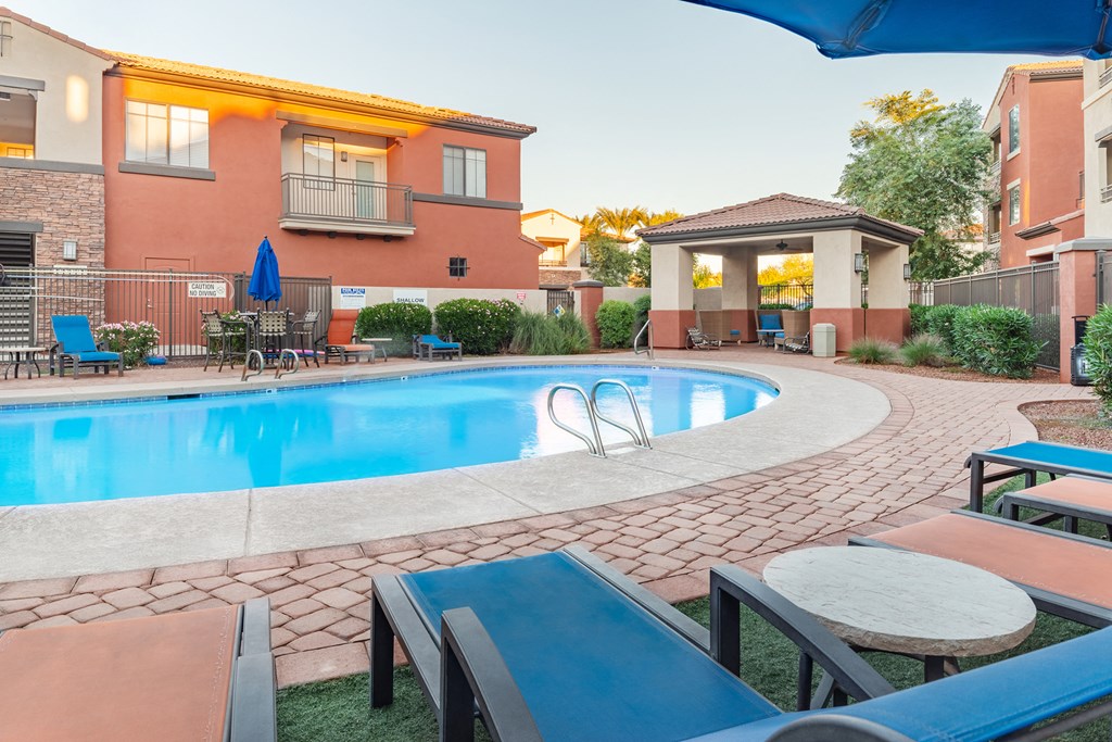 a swimming pool with lounge chairs and umbrellas in front of a building