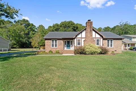 A house with a brick chimney and a green lawn.