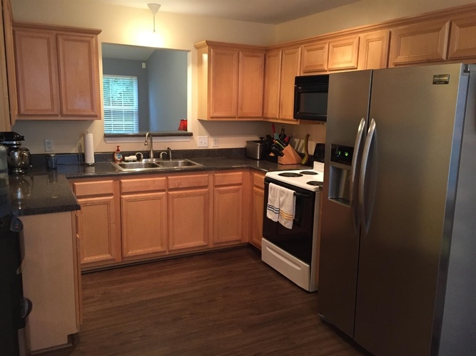 A kitchen with wooden cabinets and a stainless steel refrigerator.
