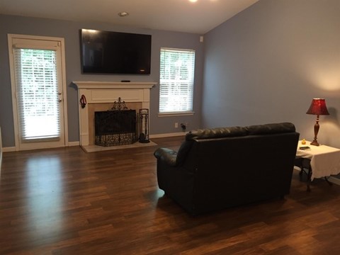 A black couch sits in a living room with a fireplace and a television.