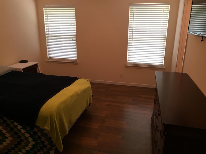 A bedroom with a bed, dresser, and window with blinds.