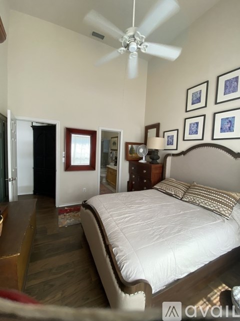 A bedroom with a bed, dresser, and ceiling fan.