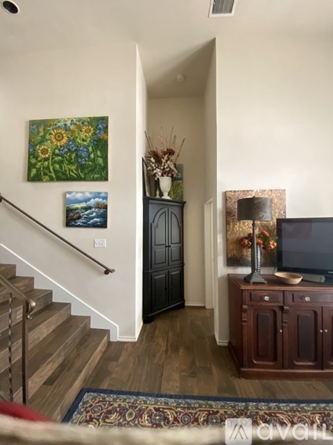 A living room with a staircase and a painting of sunflowers on the wall.