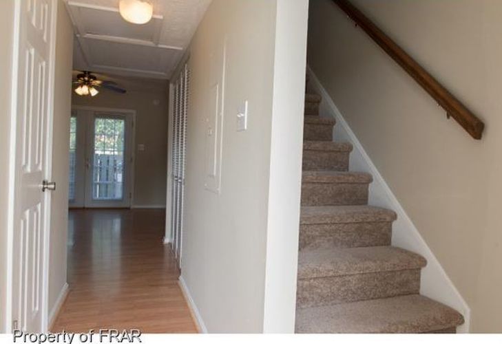 A hallway with a staircase and a door.