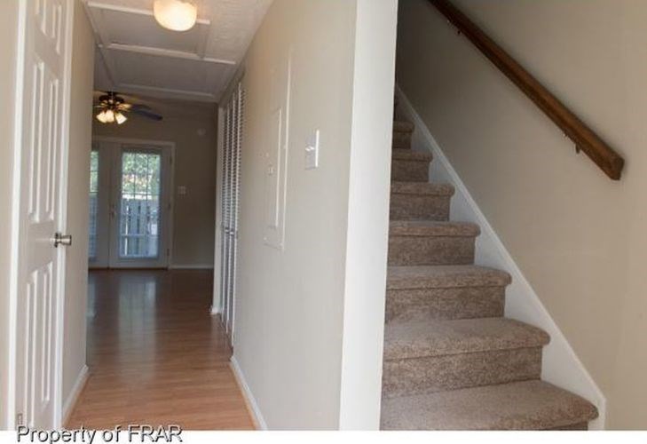 A hallway with a staircase and a door.