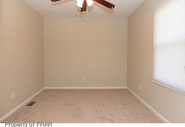 A room with a ceiling fan and a window with blinds.