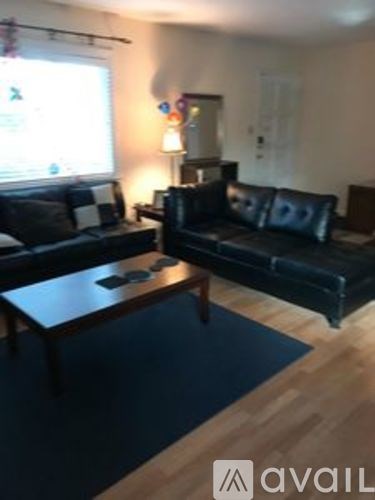A living room with a black couch and a wooden coffee table.