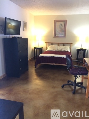 A hotel room with a bed, desk, and chair.