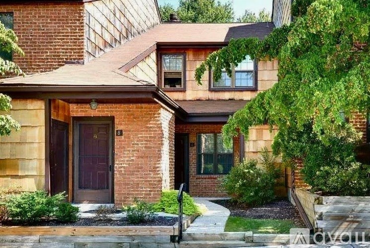 A house with a brown door and windows surrounded by greenery.
