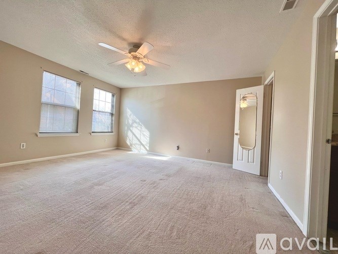 A spacious room with a ceiling fan and carpeted floor.