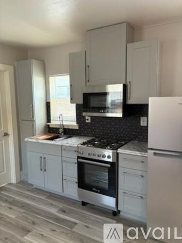 A kitchen with white cabinets and a black countertop.