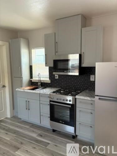 A kitchen with white cabinets and a black countertop.