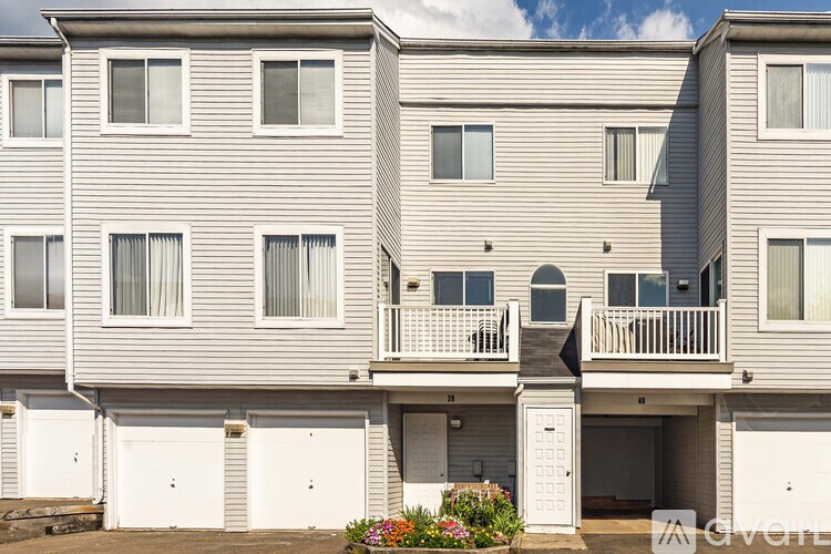 A grey apartment building with white garage doors.