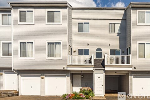 A grey apartment building with white garage doors.