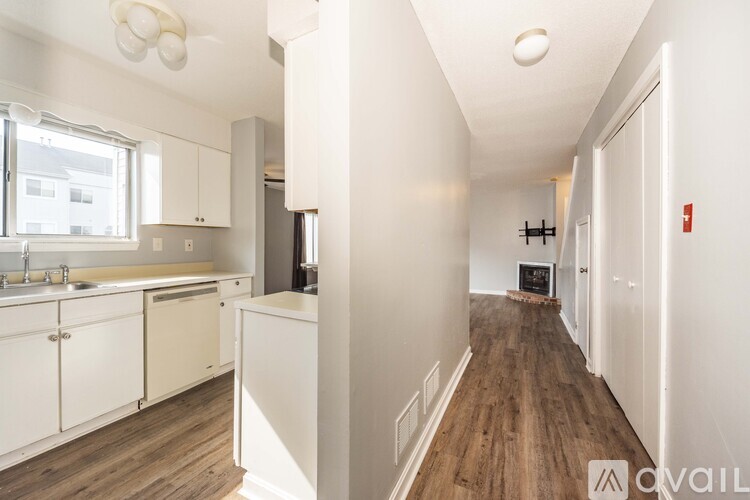 A kitchen with white cabinets and a wooden floor.