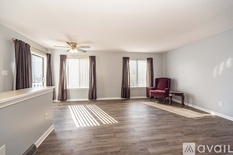 A spacious room with a red chair and a ceiling fan.