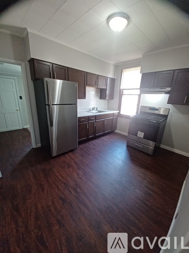A kitchen with dark wood floors and stainless steel appliances.