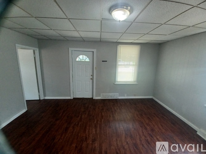 A room with wooden floors and a window with blinds.
