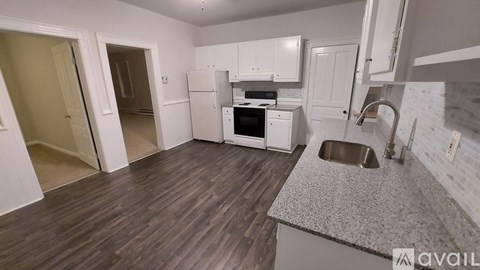 A kitchen with white appliances and wooden floors.