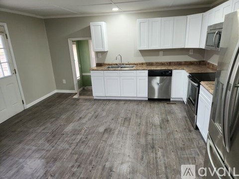 A kitchen with white cabinets and a wooden floor.