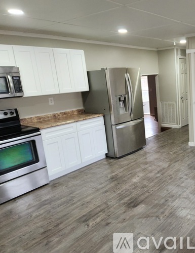 A kitchen with white cabinets and a wooden floor.