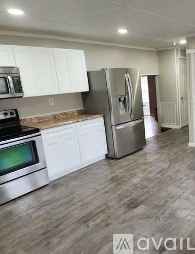 A kitchen with white cabinets and a wooden floor.