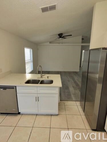 A kitchen with white cabinets and a stainless steel refrigerator.