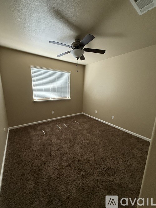 A room with a ceiling fan and carpeted floor.