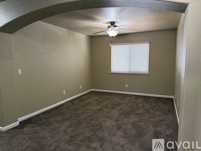 A room with a carpeted floor and a ceiling fan.