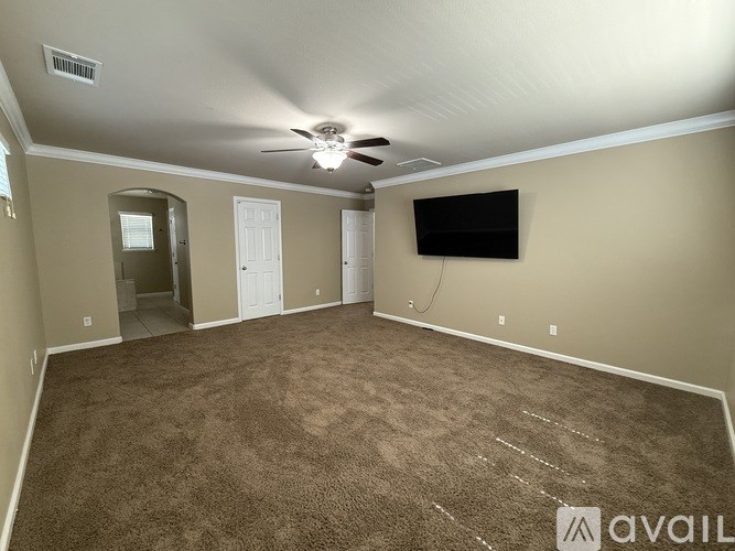 A spacious room with a carpeted floor and a ceiling fan.