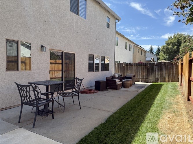 A patio with a table and chairs is in front of a house.