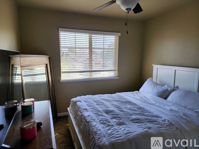 A bedroom with a bed, a dresser, and a window with blinds.
