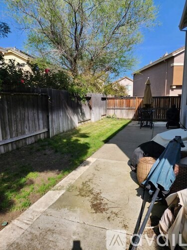 A patio with a table and chairs is in the foreground of a residential area.