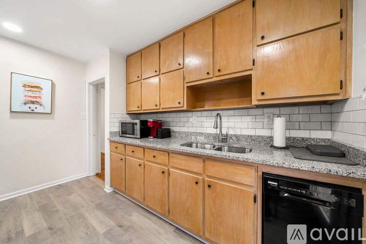 A kitchen with wooden cabinets and a black dishwasher.