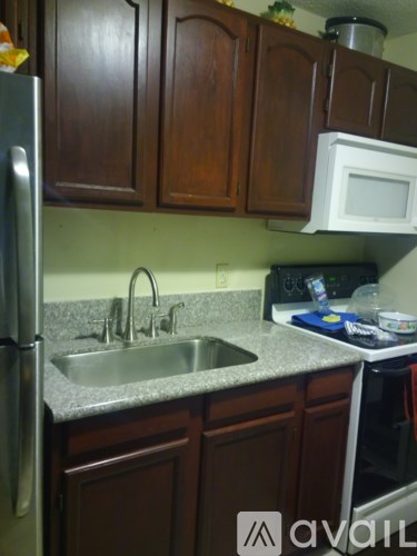 A kitchen with brown cabinets and a stainless steel refrigerator.