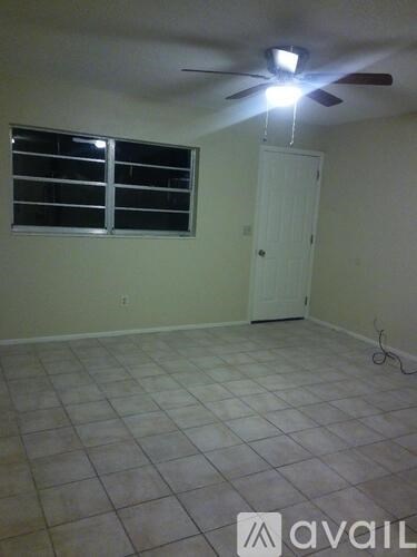 A room with a ceiling fan and a window with blinds.