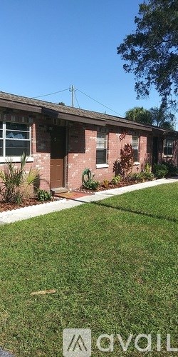 A house with a brown door and windows surrounded by green grass.