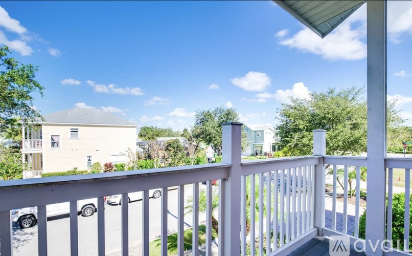 A white balcony with a view of a street and houses.