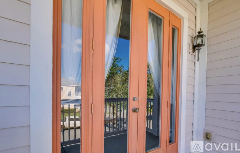 A peach-colored door with a glass window and a black railing.