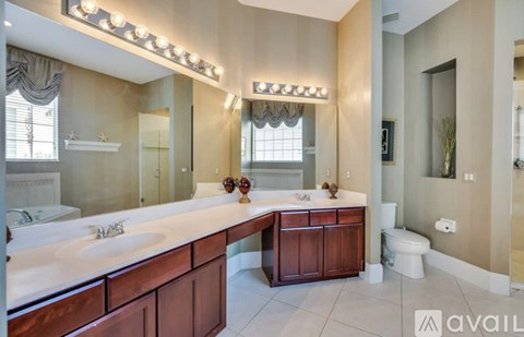 A bathroom with a large mirror and a vanity with a sink and a cabinet.